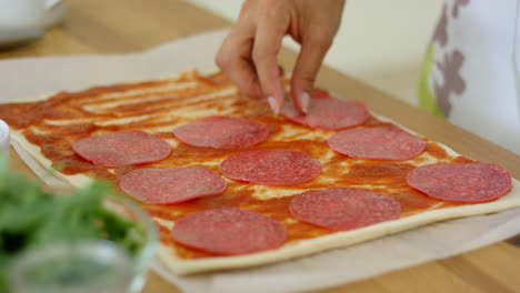 Woman-making-a-homemade-salami-and-mushroom-pizza