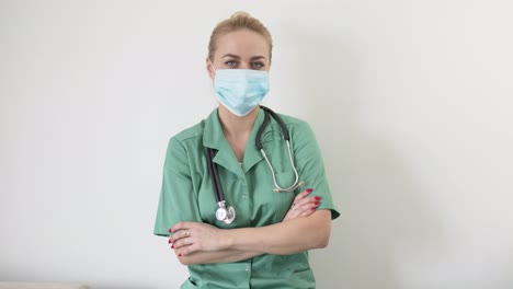 Portrait-of-young-adult-female-doctor-in-green-doctor's-coat-and-a-medical-mask