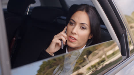 Serious-female-executive-on-phone-in-limousine