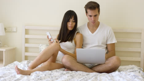 Young-serious-couple-sitting-together-in-bed