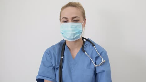 Female-nurse-or-doctor--Young-pretty-woman-in-blue-clothes-with-medical-mask-posing