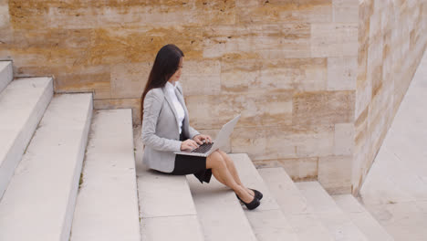 Side-view-of-woman-using-laptop-on-stairs