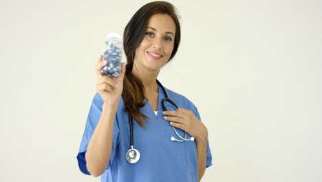 Young-brown-haired-doctor-in-scrubs-holds-bottle