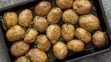 Oven-baked-whole-potatoes-with-seasoning-and-herbs-in-metalic-tray--Roasted-potatoes-in-jackets-