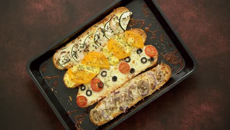 Long-baguettes-pizza-sandwiches-with-tuna--mushrooms--tomatoes-and-cheese-on-a-metal-baking-tray