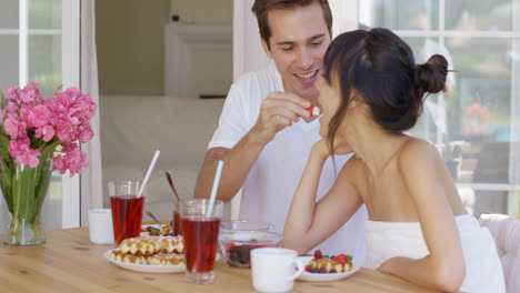 Man-feeding-his-wife-fruit-at-breakfast