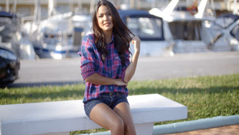 Young-Woman-Sitting-On-Bench-In-Harbor
