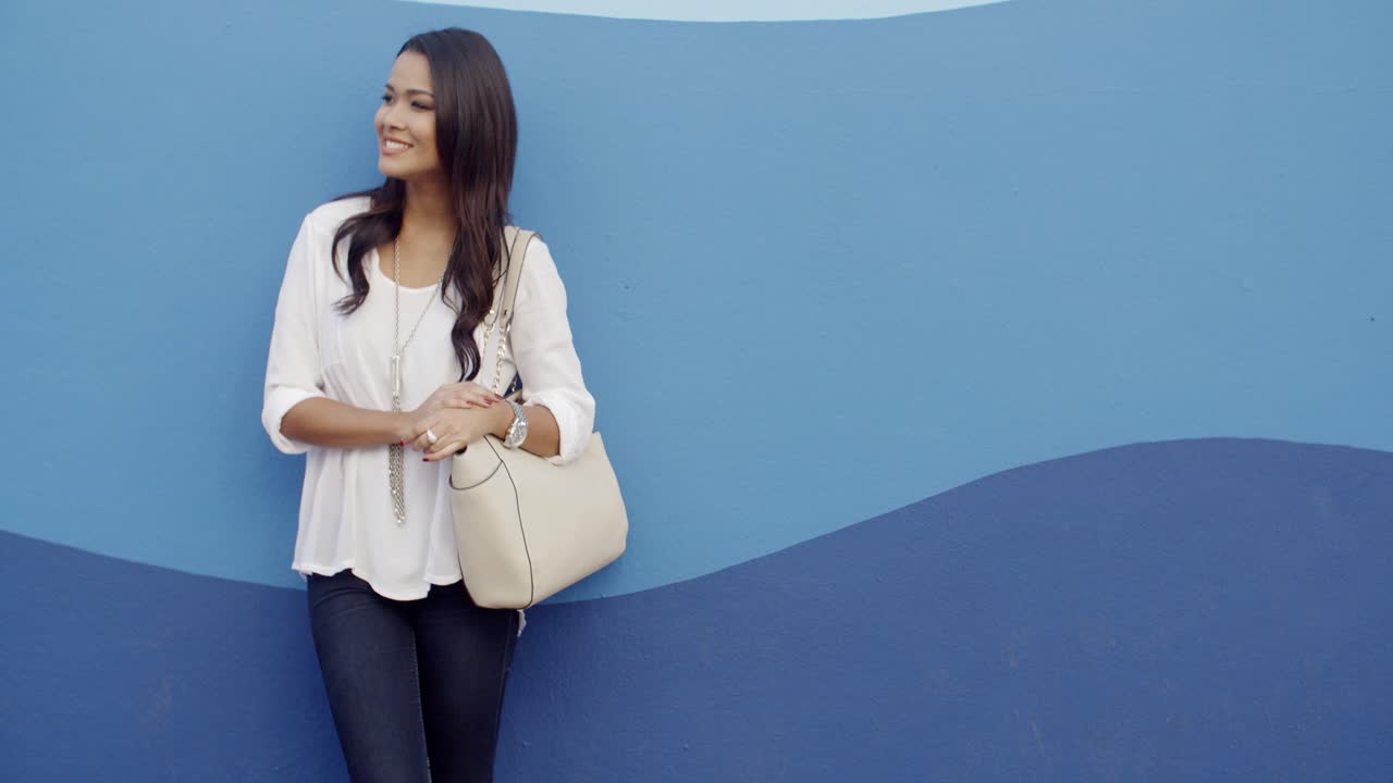 Premium stock video - Stylish cool girl against a blue wall