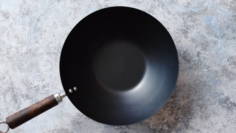 Traditional-empty-black-iron-wok-pan-placed-on-stone-background