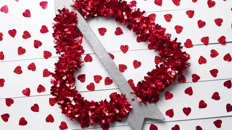 Vlentine's-Day-composition--Heart-shaped-sequins-placed-on-white-wooden-table