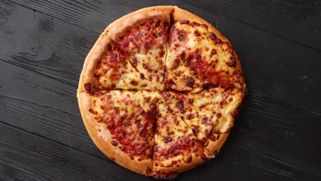 Fluffy-pepperoni-pizza-in-american-style-placed-on-rusty-old-black-wooden-table
