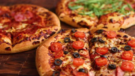 Various-kinds-of-pizzas-placed-on-wooden-table