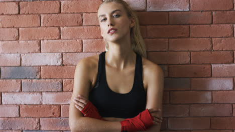 Positive-sportswoman-leaning-on-brick-wall