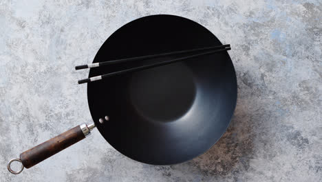 Traditional-empty-black-iron-wok-pan-placed-on-stone-background