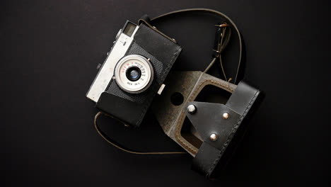 Old-retro-film-camera-in-leather-case-on-black-background