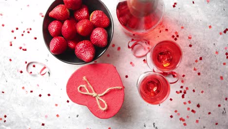 Bottle-of-rose-champagne--glasses-with-fresh-strawberries-and-heart-shaped-gift