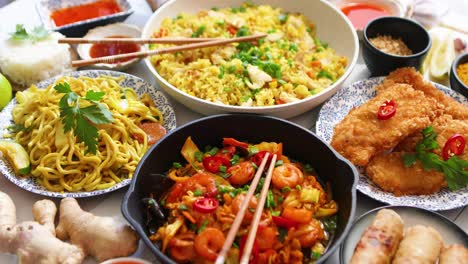 Asian-food-served--Plates--pans-and-bowls-full-of-noodles-chicken-stir-fry-and-vegetables