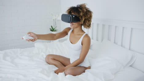 Smiling-woman-in-VR-glasses-on-bed