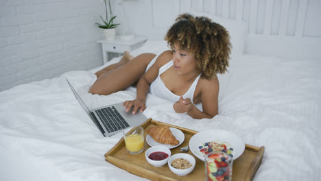 Content-woman-using-laptop-while-having-meal