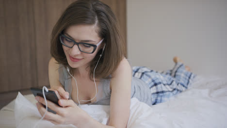 Charming-woman-in-earphones-browsing-smartphone
