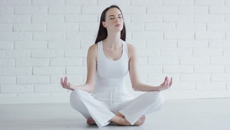Young-woman-meditating-in-white-room