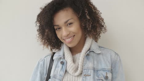 Afro-American-girl-in-casual-clothes-is-looking-at-camera-and-smiling