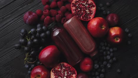 Various-fresh-red--purple-black-fruits--Mix-of-fruits-and-bottled-juices-on-black