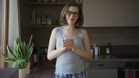 Smiling-woman-standing-in-kitchen-holding-cup