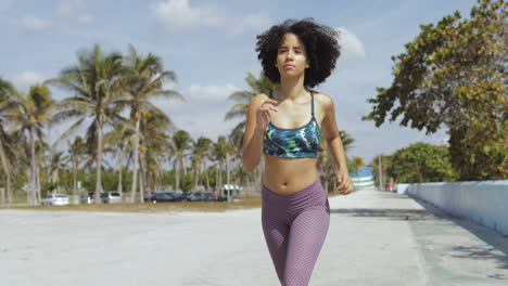 Black-fit-girl-jogging-on-tropical-waterfront