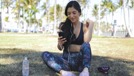 Pretty-girl-with-phone-on-workout-in-park