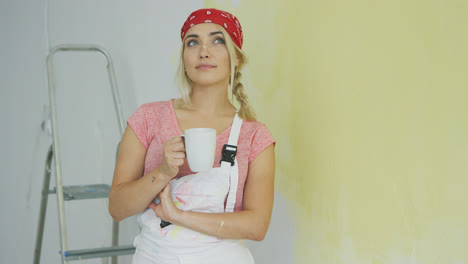 Female-painter-in-overalls-resting-with-drink-