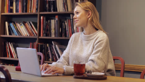 Woman-in-jumper-using-laptop-in-library