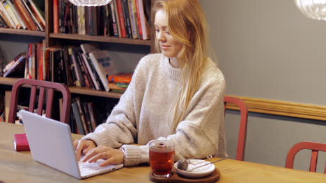 Attractive-woman-using-laptop-in-library